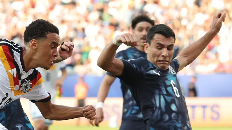 FOXBOROUGH, MASSACHUSETTS - JUNE 29: Jamal Musiala #10 of Germany crosses against Matias Galarza #23 and Junior Alonso #6 of Paraguay during the FIFA World Cup 2026 Round Of 32 match between Germany and Paraguay at Boston Stadium on June 29, 2026 in Foxborough, Massachusetts. (Photo by Alexander Hassenstein/Getty Images)